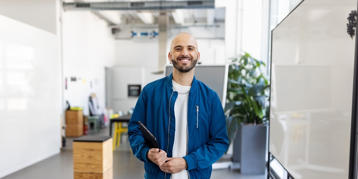 man smiling in office, holding laptop