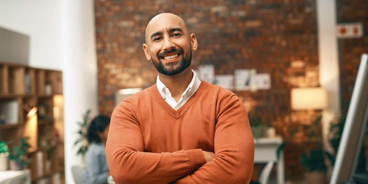 smiling man in orange sweater with arms crossed