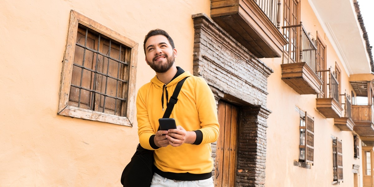 man walking past yellow building smiling