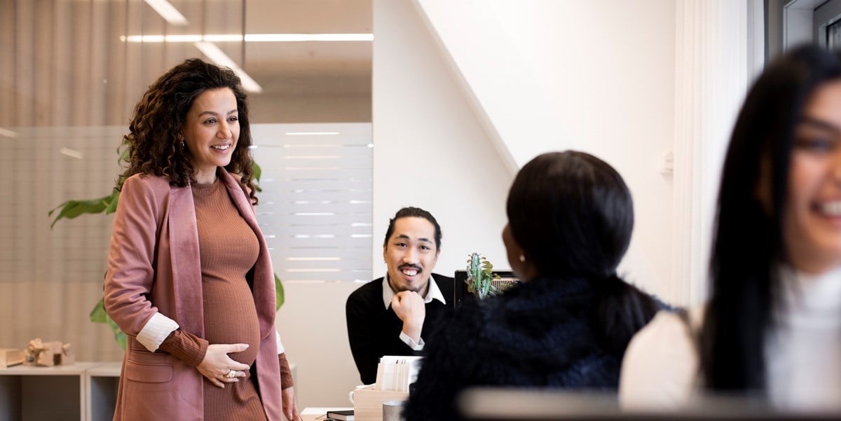 professional woman speaking to colleagues seated at a table