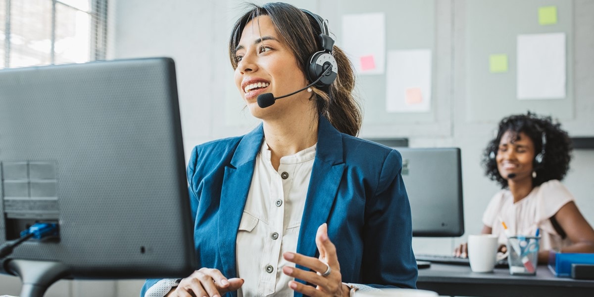 professional woman in office, at desk, wearing headset