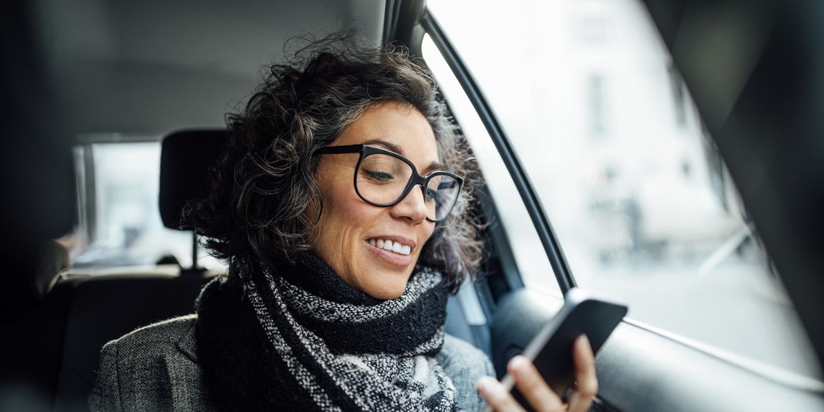 woman travelling in a car, looking at cellphone