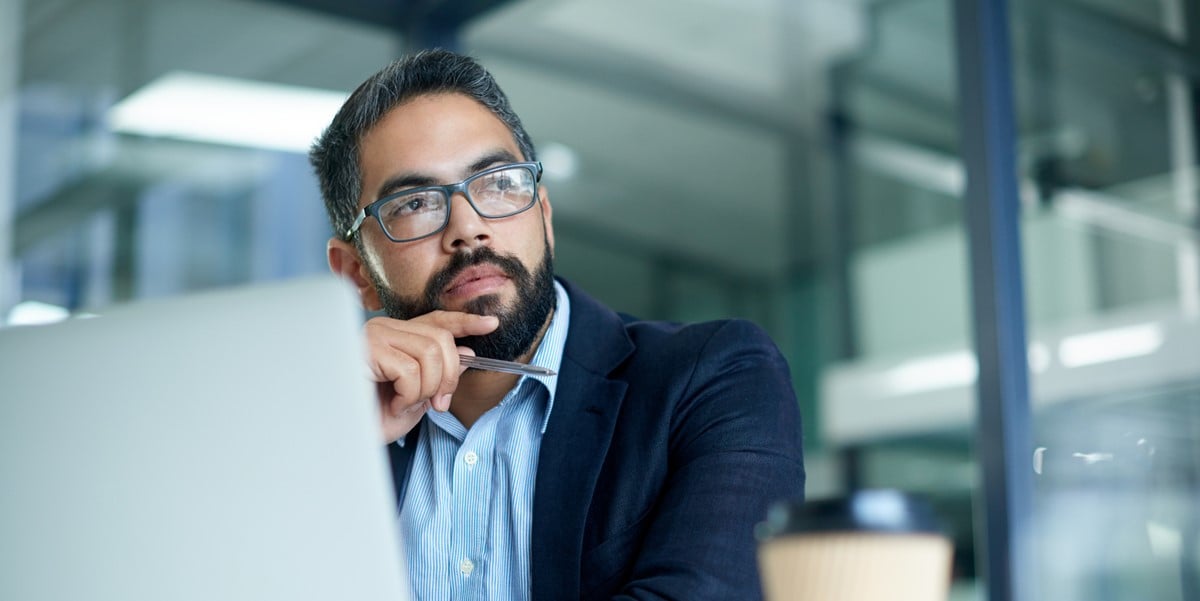 professional man in office working at desk, looking outward